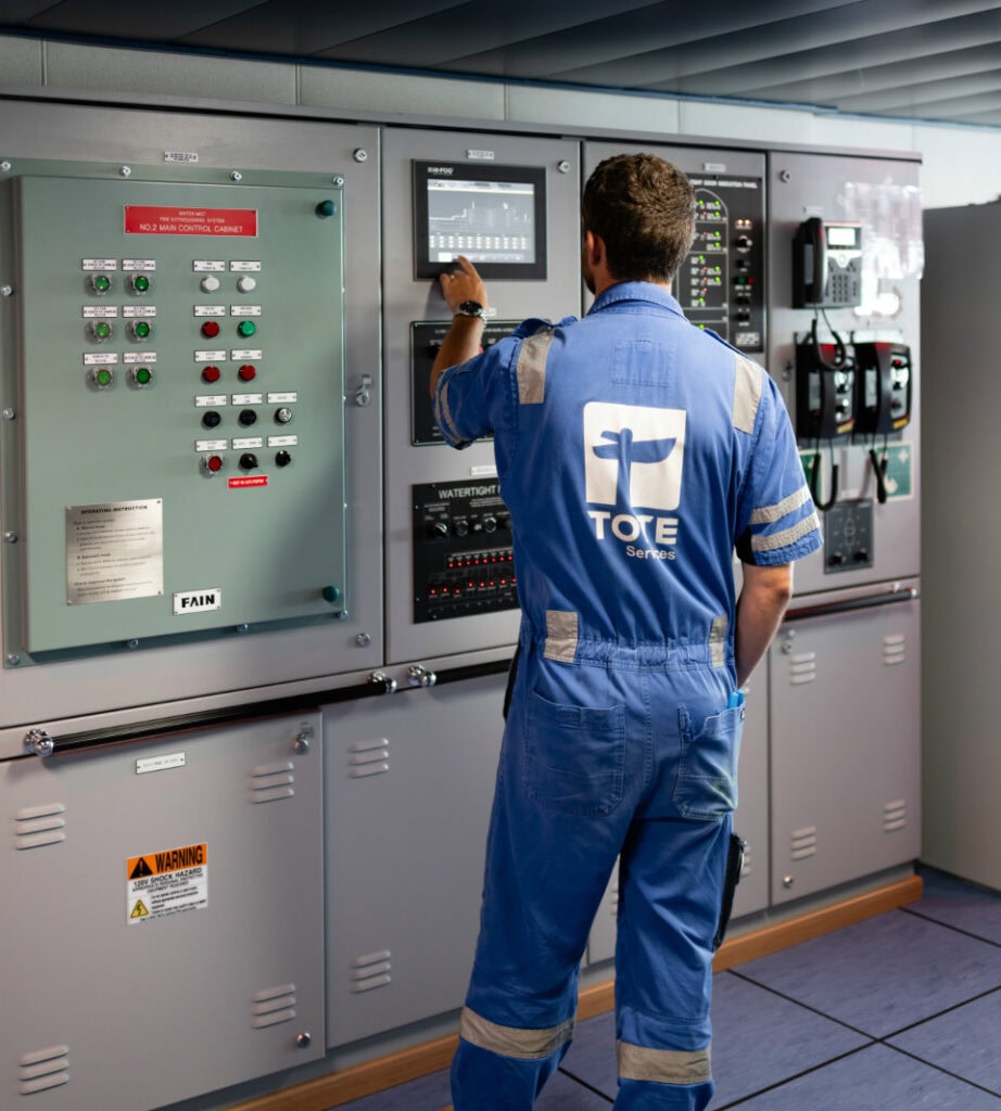 Technician operating control panel in industrial setting.