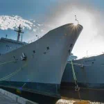 Close-up of the bow of a large ship docked at a port.