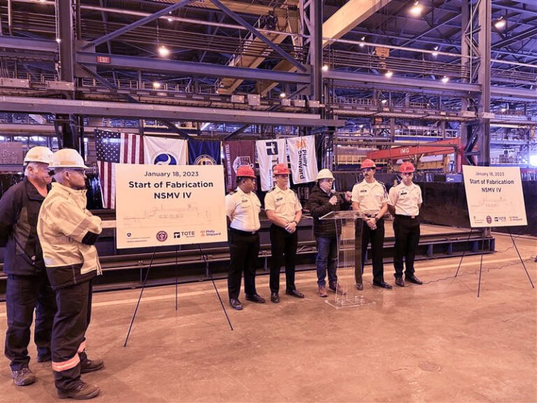 Group of people in safety gear at a factory start of fabrication event.