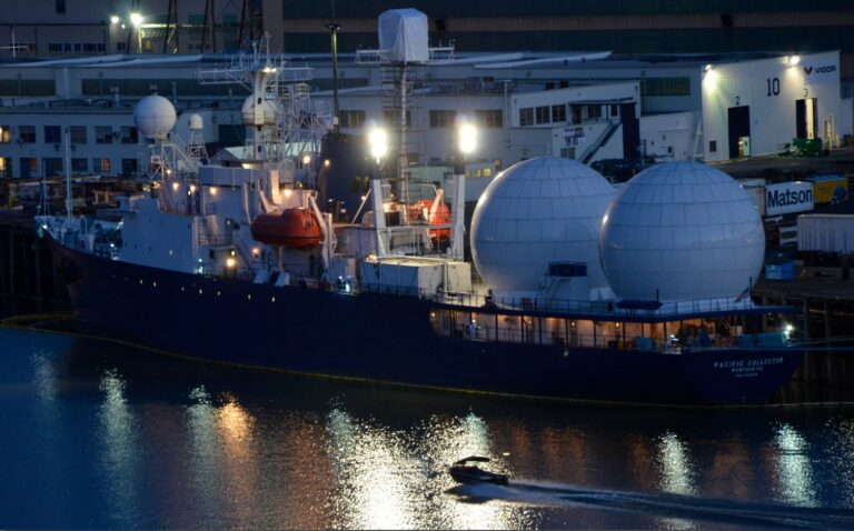 Pacific Collector ship docked at port with large radar domes and industrial buildings in the backgro.