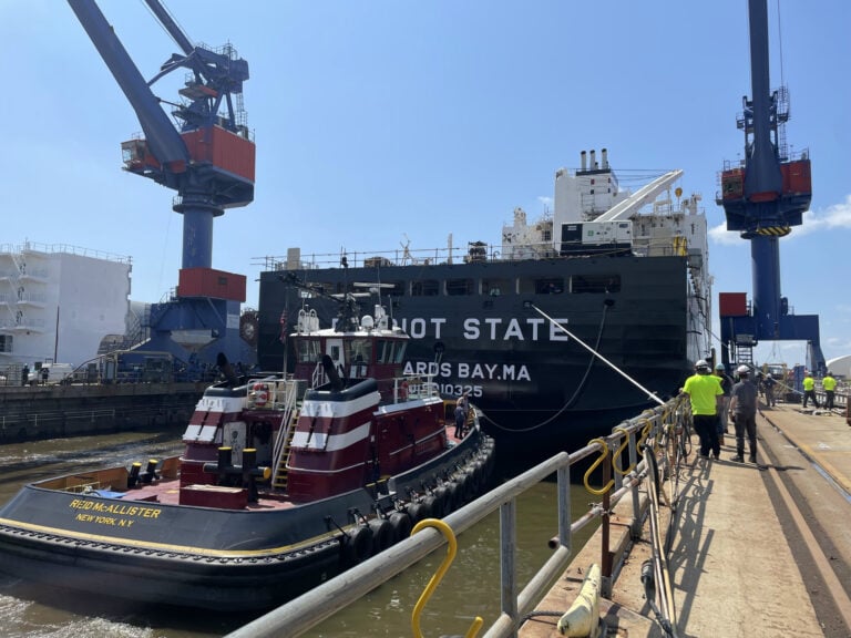 Large cargo ship docked at port with cranes in the background.