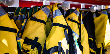 Life jackets hanging on a rack, ready for emergency use.