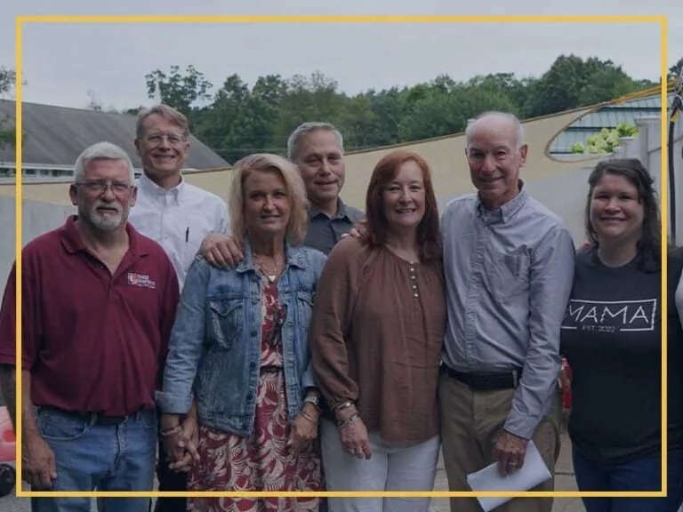 Seven people standing outdoors, smiling for the photo.