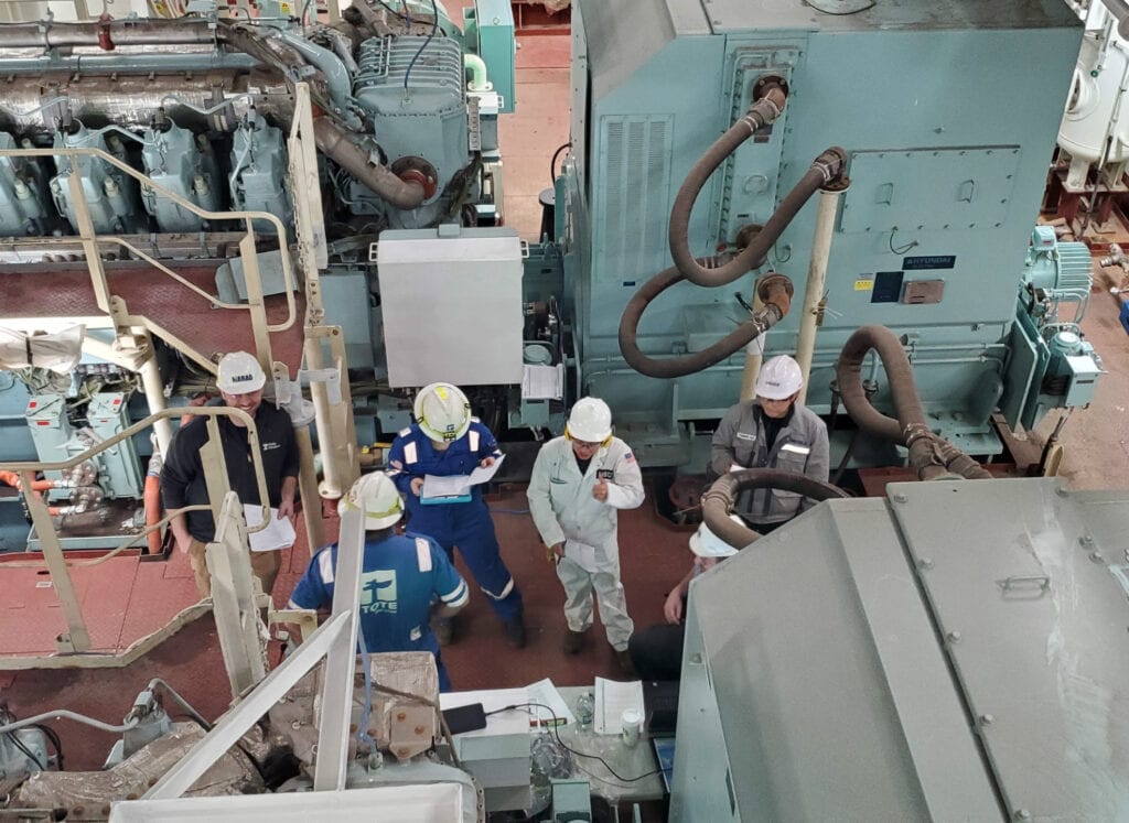 Workers inspecting machinery in an industrial facility.