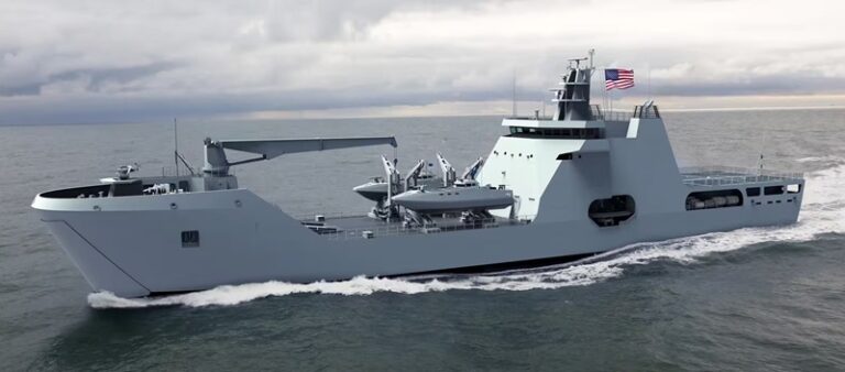 Large gray military landing ship sailing on the ocean with a helicopter on deck.