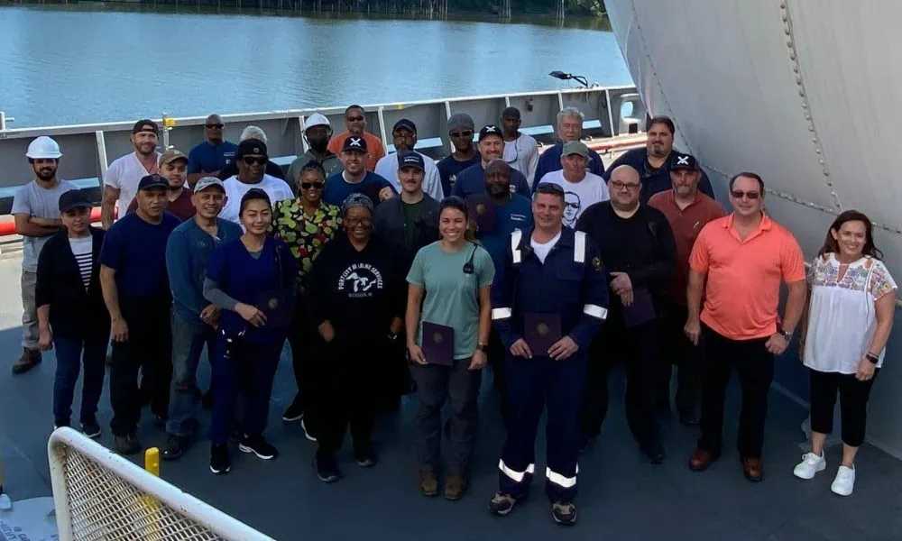 Group of people standing on a ship deck near the water.