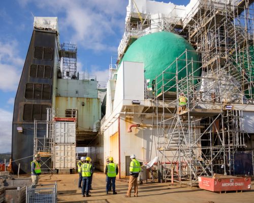 NSShipyard2023-50 – TOTE Services Large industrial ship under construction with scaffolding and workers on deck.