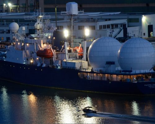 Pacific Collector ship docked at port with large radar domes and industrial buildings in the backgro.