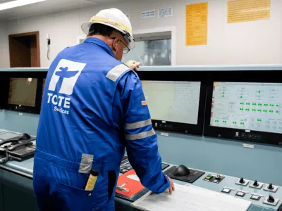 emissions control Worker in blue uniform and helmet operating control panel at TOTE Services.