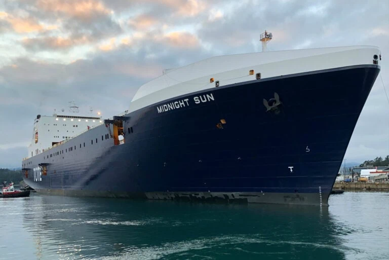 Large cruise ship named MIDNIGHT SUN docked at port with cloudy sky.