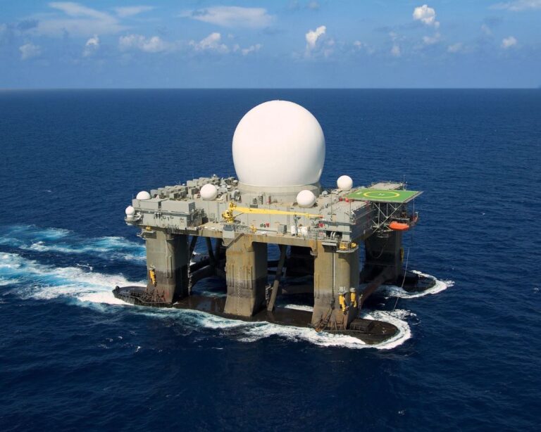Large offshore platform with a spherical radar dome and communication equipment in the ocean.